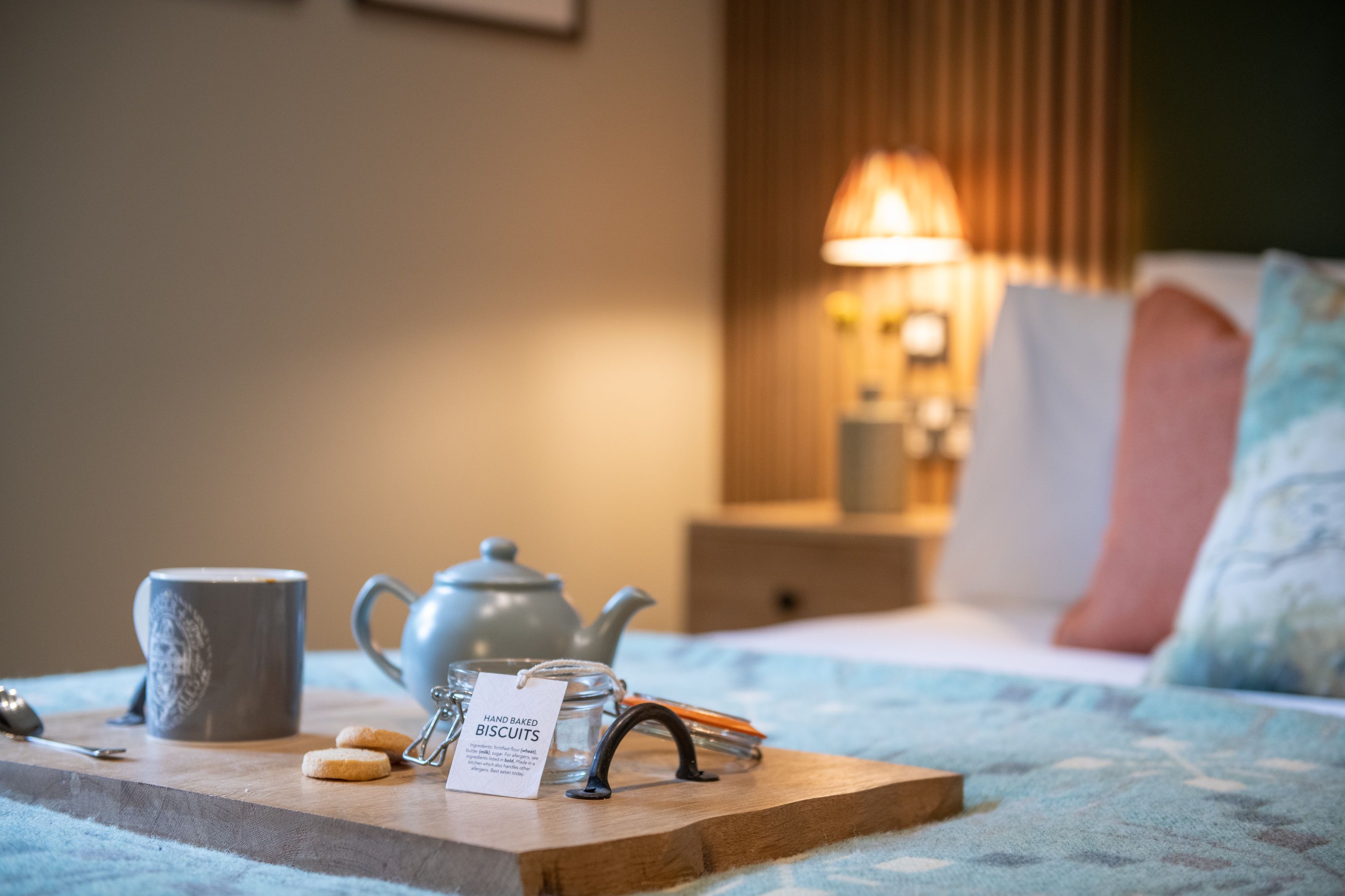 Teapot and handmade biscuits on a tray on the bed