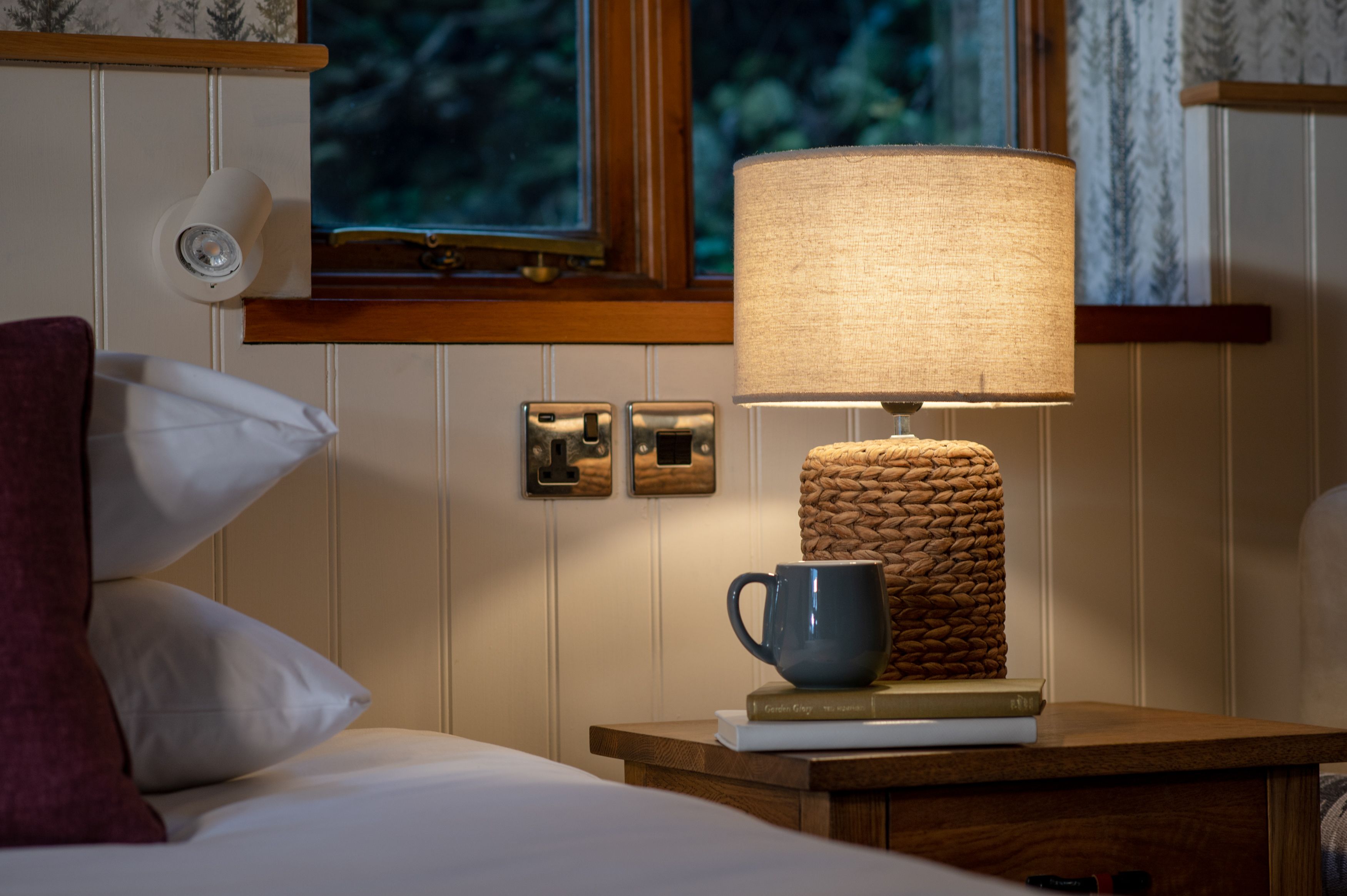 Lamp on bedside table with books and mug