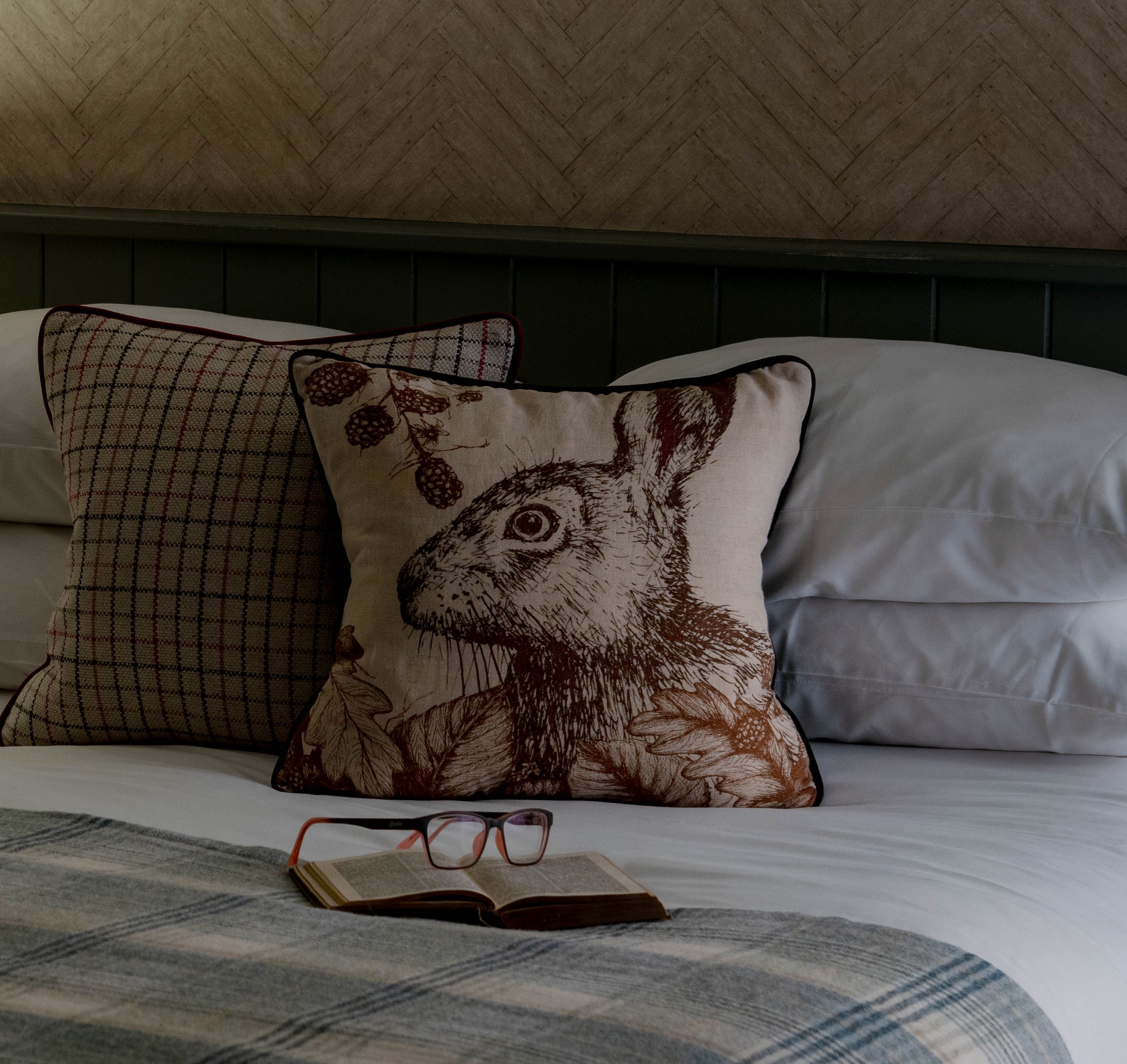 Rabbit cushion on bed with book and reading glasses