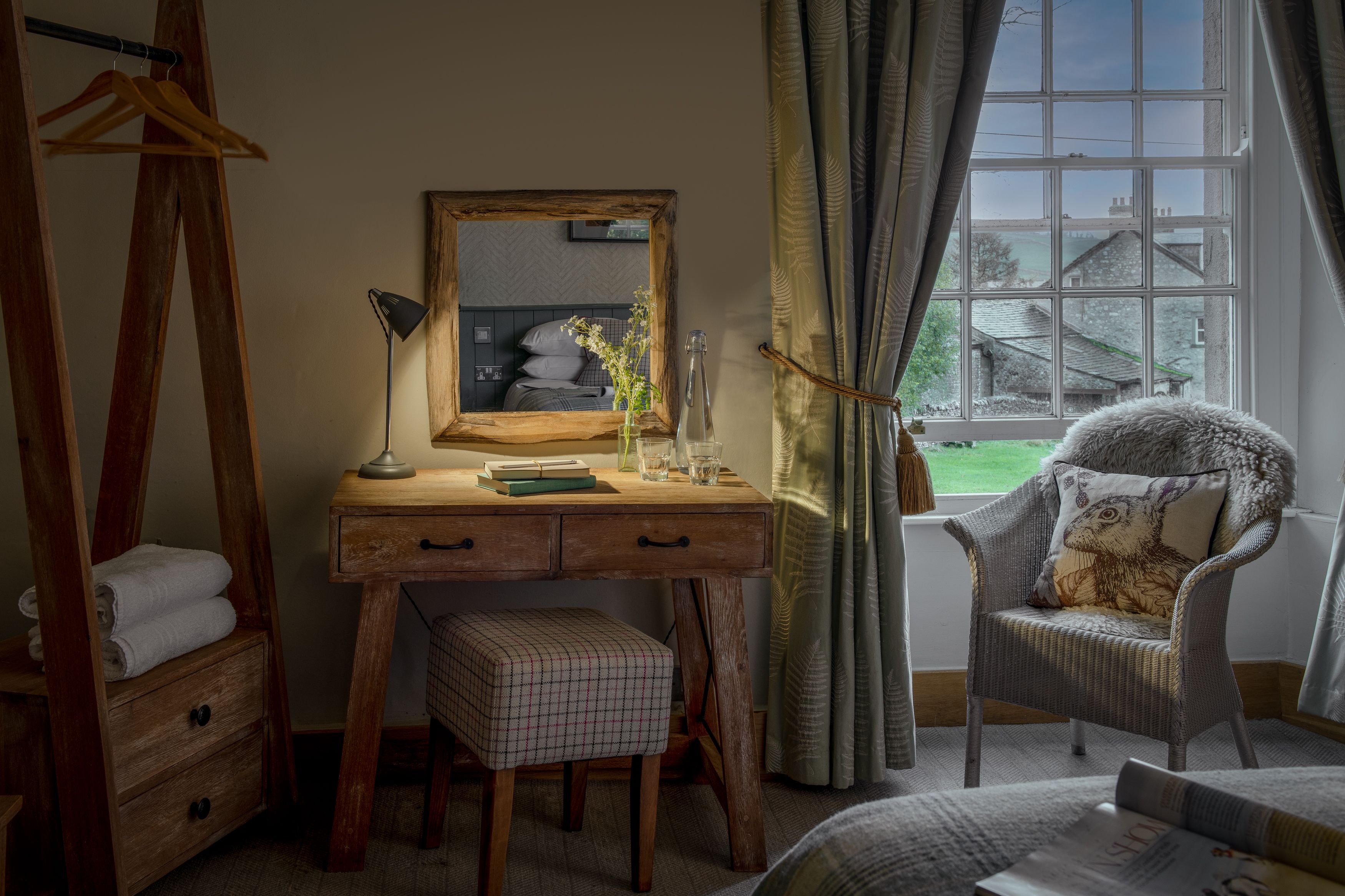 Dressing table with mirror and stool with arm chair looking out of the window